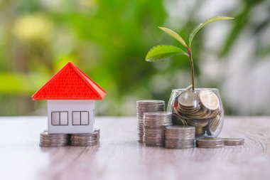 Turuncu çatı evleri şişelere tohum yetiştiren madeni paralar ve madeni paralar koydular. Tasarruf, ev ve ipotek, gayrimenkul ve yatırım, büyüme için ev satın alma kavramları.