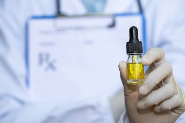 Doktorlar ya da araştırmacılar bir şişe kenevir yağı tutuyor. Tıbbi reçetelerle, marihuanayla, tehlikeli hastalıkların tedavisinde kullanılan alternatif ilaç özgeçmişi. Tıbbi marihuana.