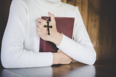 Genç bir kadın İncil 'e sarıldı ve elinde bir haç tuttu. Tanrı 'nın kutsal bir kutsaması olarak kabul edilir. Hristiyanlara ibadet ve övgü ve dini inançlar. Bir lütuf istiyorum..