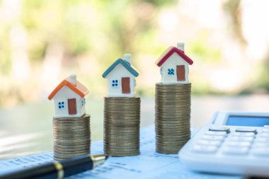 Bozuk paraların üzerine yerleştirilen ev, emlak merdiveni ve ipotek konsepti almak için tasarruf parası biriktirmeyi planlıyor. Para biriktirme kavramı, madeni para yığını büyütme işi, yatırım için para biriktirme.