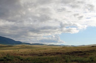 Beyaz bulutlar Sayan Dağları Sibirya Rusya ile mavi gökyüzü altında sarı çim ile geniş bozkır