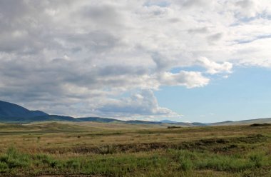 Beyaz bulutlar Sayan Dağları Sibirya Rusya ile mavi gökyüzü altında sarı çim ile geniş bozkır