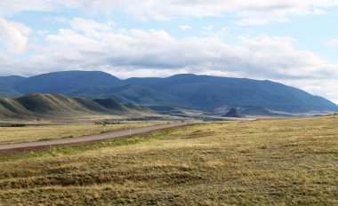Beyaz bulutlar Sayan Dağları Sibirya Rusya ile mavi gökyüzü altında sarı çim ile geniş bozkır