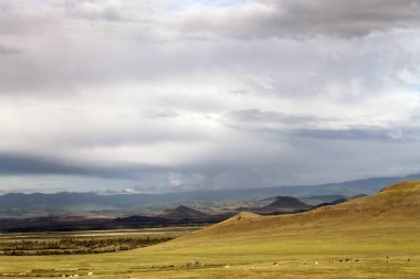 Beyaz bulutlar Sayan Dağları Sibirya Rusya ile mavi gökyüzü altında sarı çim ile geniş bozkır