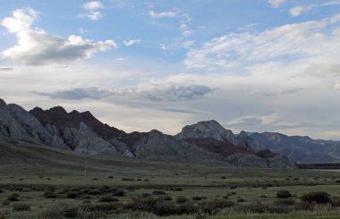 Beyaz bulutlar Sayan Dağları Sibirya Rusya ile mavi gökyüzü altında sarı çim ile geniş bozkır
