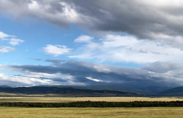 Estepa larga com grama amarela sob um céu azul com nuvens brancas Montanhas Sayan Sibéria Rússia — Fotografia de Stock