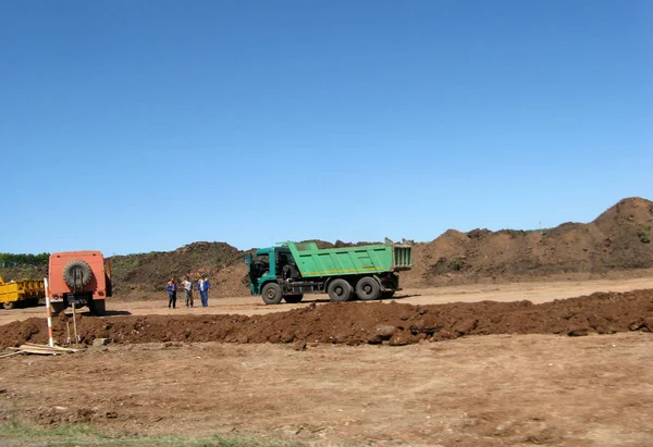 Road working on the new road construction site. Highway road works construction build machinery dump-body truck — Stock Photo, Image