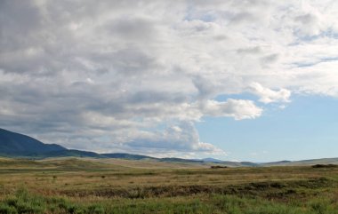 Beyaz bulutlar Sayan Dağları Sibirya Rusya ile mavi gökyüzü altında sarı çim ile geniş bozkır. güzel hill