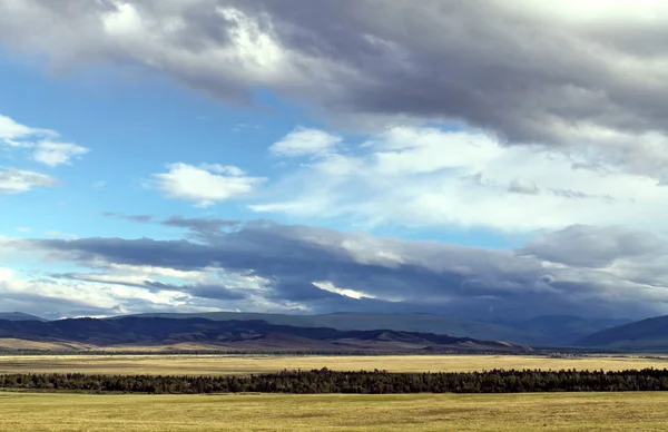 Estepa larga com grama amarela sob um céu azul com nuvens brancas Montanhas Sayan Sibéria Rússia — Fotografia de Stock