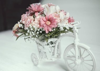Oyuncak bisikletle beyaz sepetin içinde düğün buketi