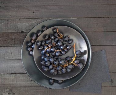 Tahta masada siyah tabakta siyah üzümlerin üst görüntüsü