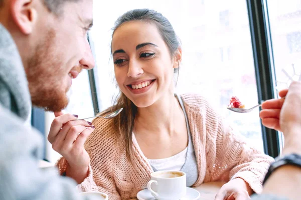 couple eating a dessert spoon in cafe on date