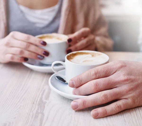 Hands on the table holding cups of coffee — Stock Photo, Image