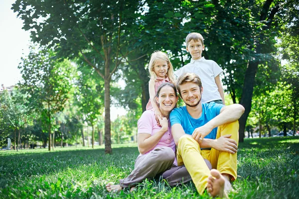 Familj vid middagstid i parken på gräset — Stockfoto