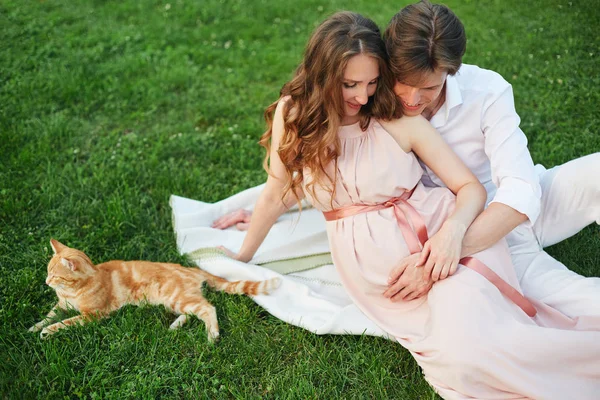 怀孕的女人坐在草地上，抚摸着她的肚子 — 图库照片