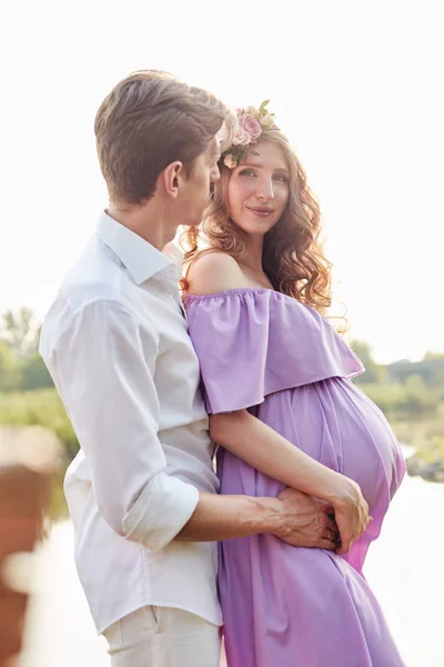 Schwangere Frau und ihr Mann spazieren abends in Park — Stockfoto