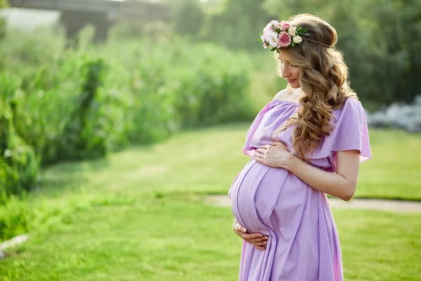 Pregnant woman walks in park at evening — Stock Photo, Image