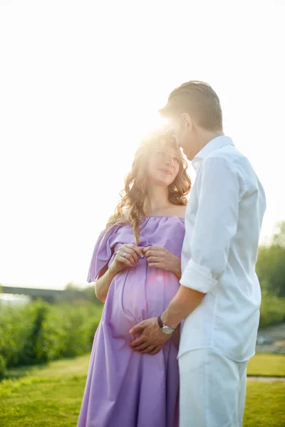Pregnant woman and her husband walks in park at evening — Stock Photo, Image