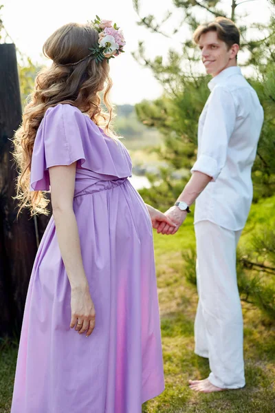 Schwangere Frau und ihr Mann spazieren abends in Park — Stockfoto