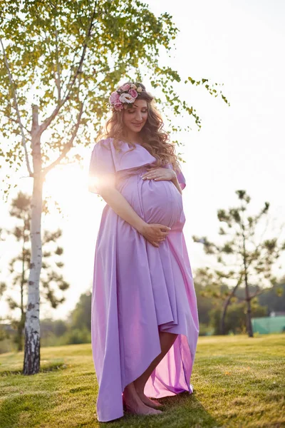 Pregnant woman walks in park at evening — Stock Photo, Image