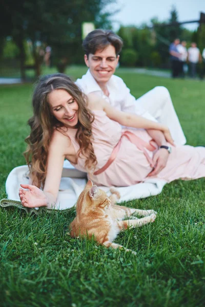 Pregnant woman sitting on the grass and stroking her stomach — Stock Photo, Image