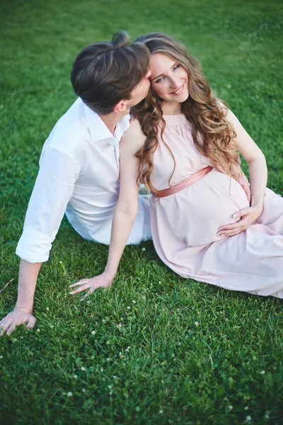 Pregnant woman and her husband walks in park at evening — Stock Photo, Image