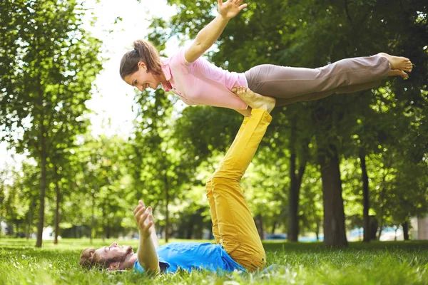 Linda pareja haciendo acro yoga en el parque en un día soleado — Foto de Stock