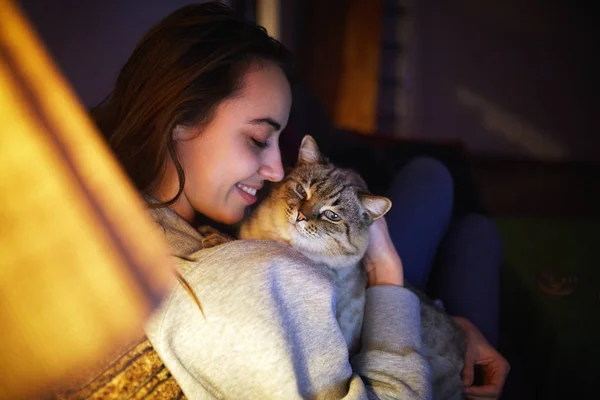 Молода жінка з кішкою ввечері — стокове фото