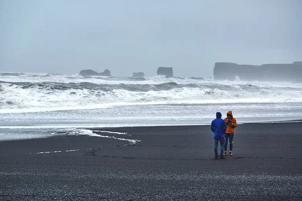 Menschen spazieren am schwarzen Sandstrand von Reynisfjara im Süden von Island — Stockfoto