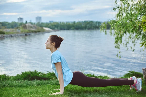 Retrato de mujer joven y deportiva en ropa deportiva haciendo yoga o ejercicios de estiramiento — Foto de Stock