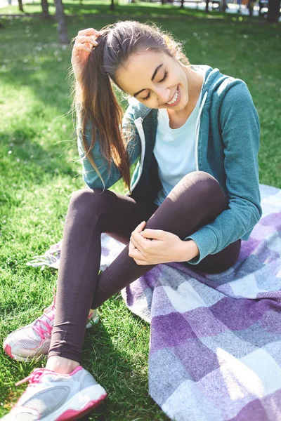 Retrato de una hermosa mujer feliz se sienta en la hierba en el Parque — Foto de Stock