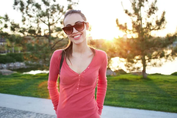 Mooi jong meisje in een roze jas staat op de promenade aan de rivier — Stockfoto