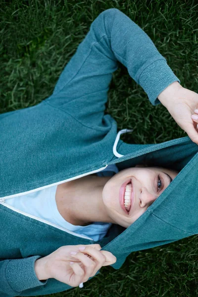 Portrait of young and sporty woman in sportswear lies on the grass in park — Stock Photo, Image