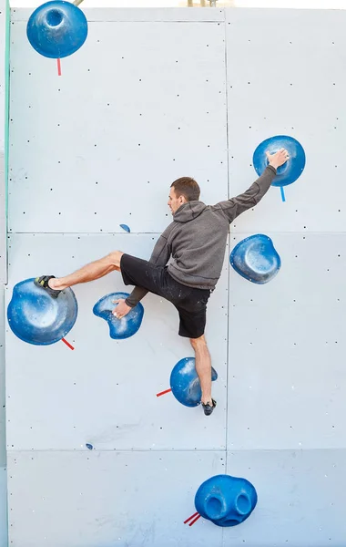 Escalador hombre sube un problema de bouldering en gimnasio de escalada — Foto de Stock