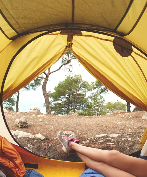 Näkymä metsäteltan sisältä ja naisen jalat ilmestyvät teltasta — kuvapankkivalokuva