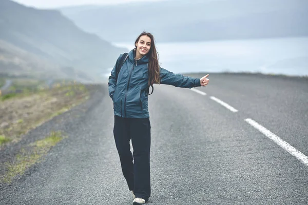 Žena turista na prázdné silnici na fjord na Islandu — Stock fotografie