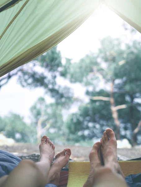 Näkymä sisältä teltta metsässä ja jalat kaksi ihmistä ulos teltasta — kuvapankkivalokuva