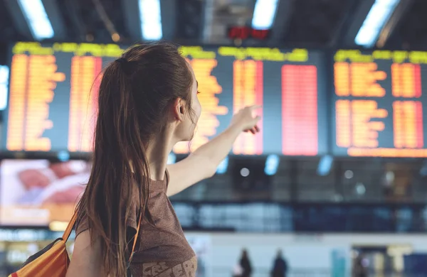Молодая женщина в международном аэропорту глядя на борд информации о рейсах — стоковое фото
