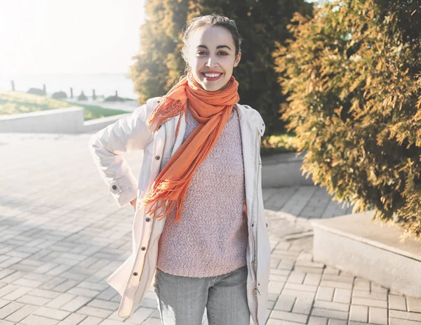 Una hermosa joven con una capa beige a pie en otoño — Foto de Stock