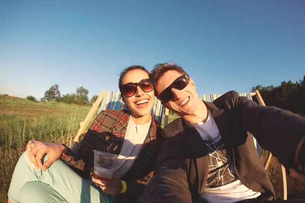 Hymyilevä pari tekee selfie ja lepää kansituolilla — kuvapankkivalokuva