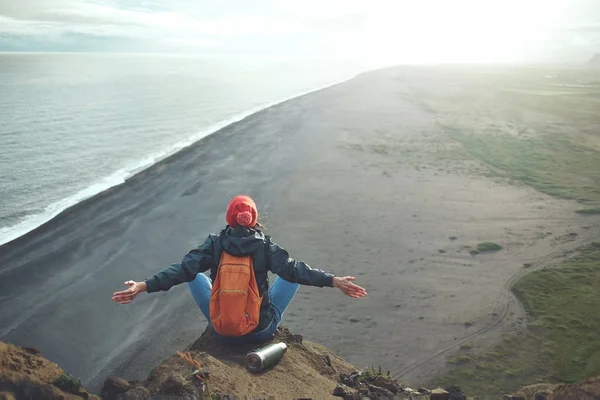 Kvinne på fottur med ryggsekk som står på et fjell og nyter solnedgang på Island – stockfoto