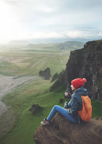 Randonneuse avec sac à dos assis au sommet d'une montagne et profitant du coucher de soleil en Islande — Photo