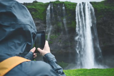 İzlanda'daki şelale altında yürüyen uzun yürüyüşe çıkan kimse kadın