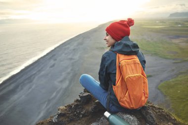 bir dağın tepesinde duran ve günbatımı İzlanda'zevk sırt çantası ile kadın uzun yürüyüşe çıkan kimse