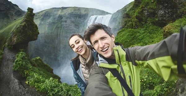 Улыбающаяся счастливая пара делает селфи на фоне водопада Скогафосс — стоковое фото