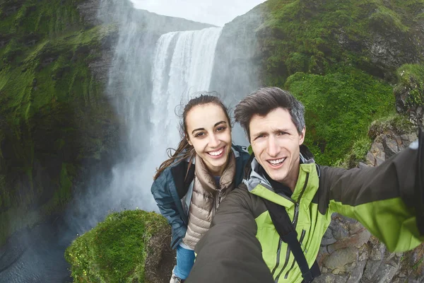 Улыбающаяся счастливая пара делает селфи на фоне водопада Скогафосс — стоковое фото