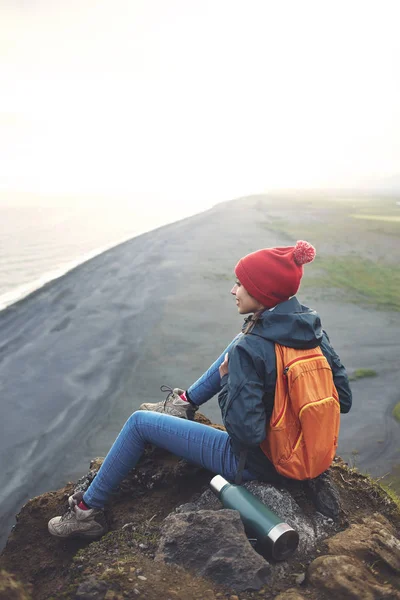 Nainen retkeilijä reppu seisoo vuoren huipulla ja nauttia auringonlaskusta Islannissa — kuvapankkivalokuva