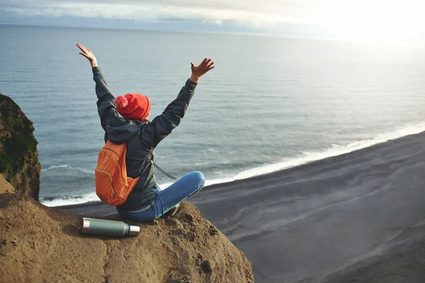 Nainen retkeilijä reppu seisoo vuoren huipulla ja nauttia auringonlaskusta Islannissa — kuvapankkivalokuva