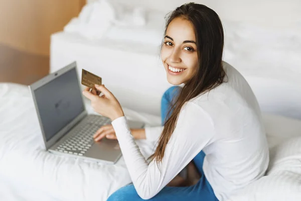 Nuori hymyilevä nainen kannettavan tietokoneen ja luottokortin kanssa — kuvapankkivalokuva