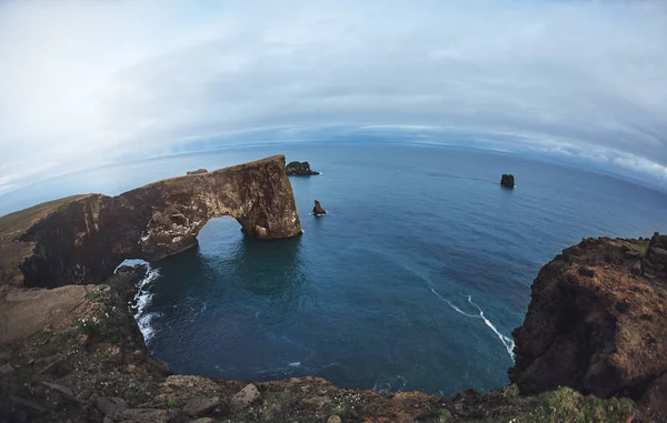 Удивительная черная арка лавы, стоящая в море на маленьком полуострове . — стоковое фото